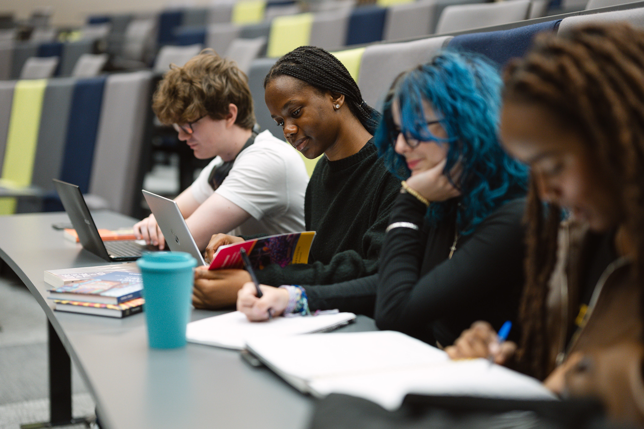 A group of young students in a lecture hall at a university of college, studying.