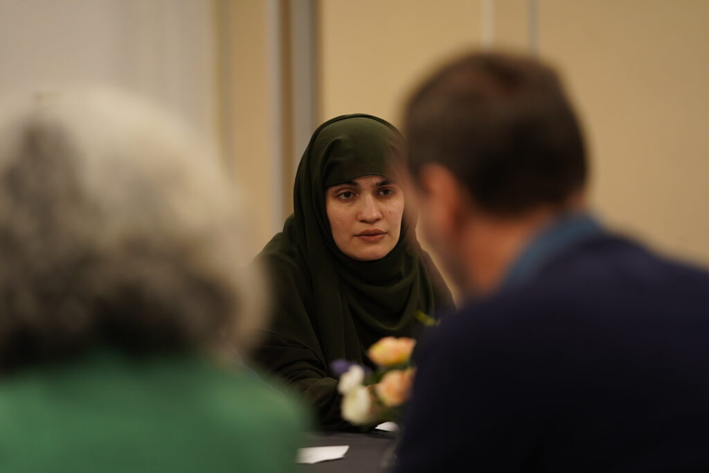 Image featuring a Hijab-wearing woman at a table in conversation with 2 project partners